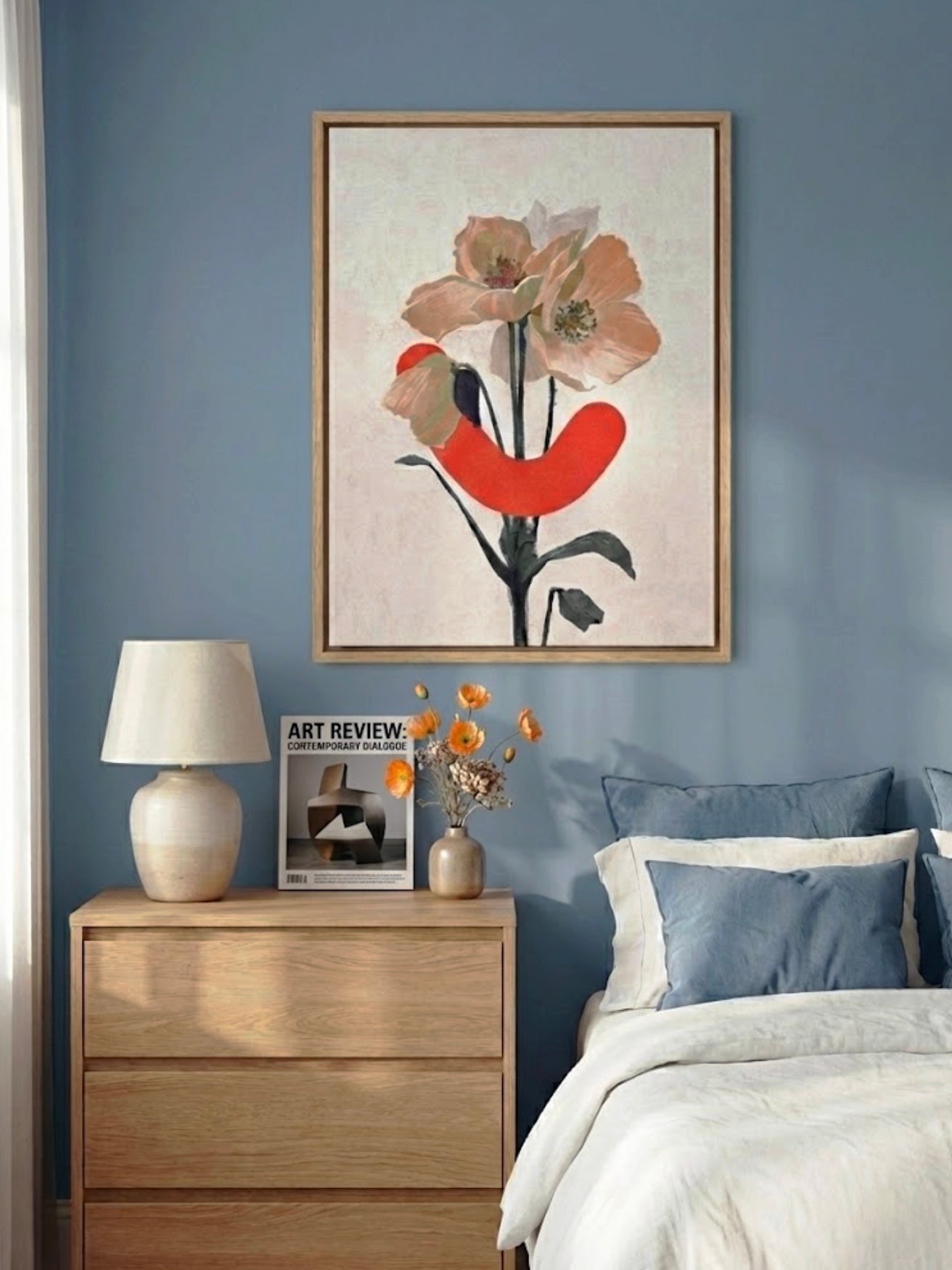 Bedroom with floral artwork on the wall, wooden nightstand, and bed with blue pillows.