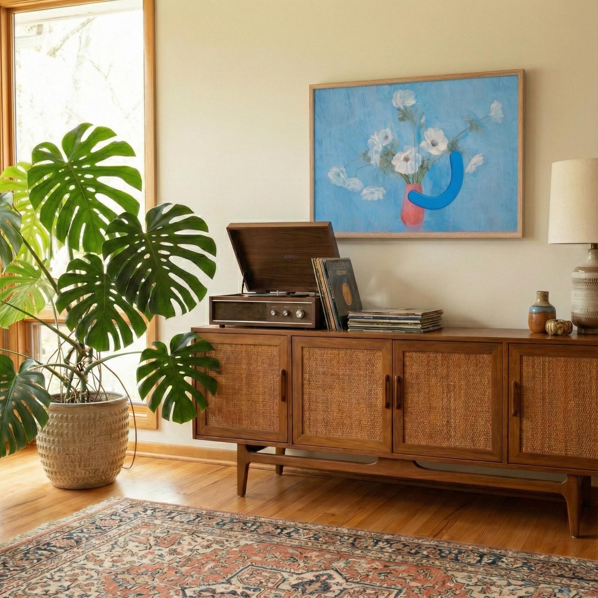 Wooden sideboard with vinyl records, plant, and artwork in a room with a rug and window.