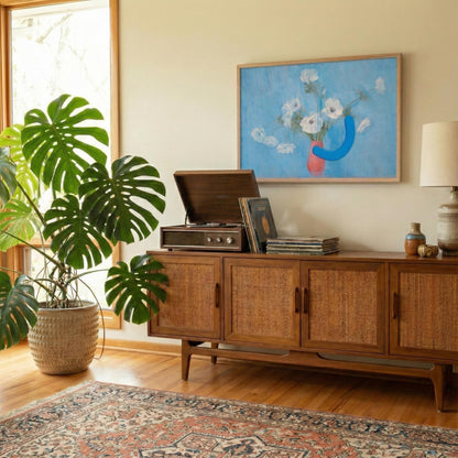 Wooden sideboard with vinyl records, plant, and artwork in a room with a rug and window.